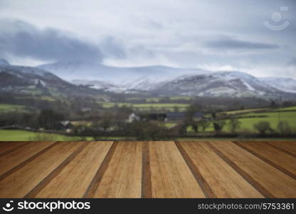 Countryside landscape with snow covered mountain range in distance with wooden planks floor