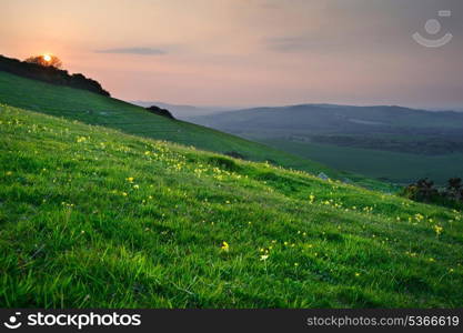 Countryside landscape with sun setting over green hills