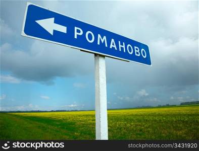 Countryside meadow and directional road sign.