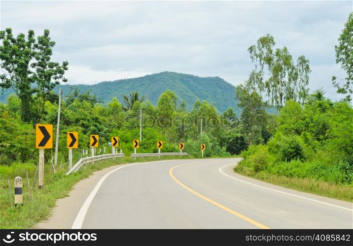 Countryside road with warning curve road sign