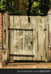 Countryside scene. Rustic old wooden gate in brick wall.