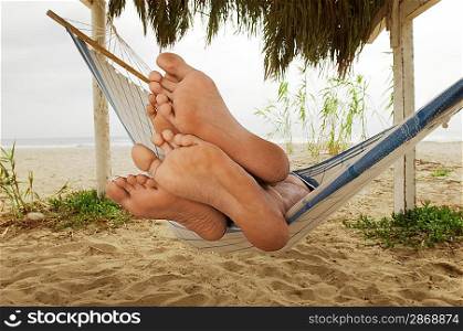 Couple&acute;s Feet on Edge of Hammock on Beach