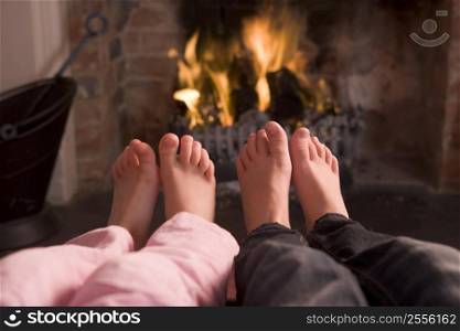 Couple&acute;s feet warming at a fireplace
