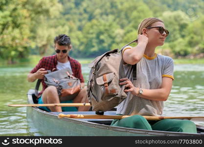 Couple adventurous explorer friends are canoeing in a wild river surrounded by the beautiful nature