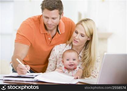 Couple and baby in dining room with laptop