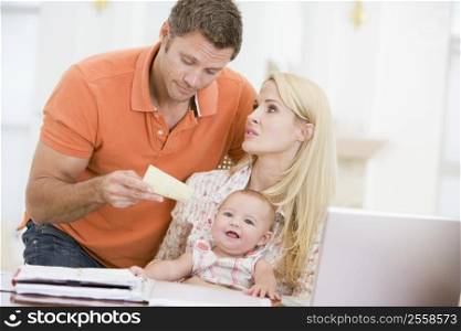 Couple and baby in dining room with laptop and paperwork