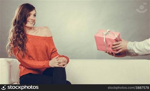 Couple and holiday concept. man holding present in hands surprising cheerful woman with gift box