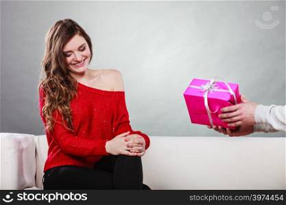 Couple and holiday concept. man holding present in hands surprising cheerful woman with gift box