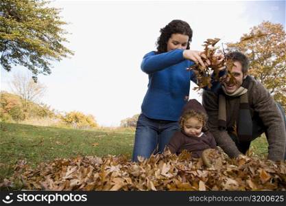 Couple and their daughter playing with leaves