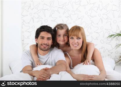 couple and their little girl in bed