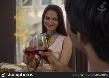 Couple at bar toasting red wine