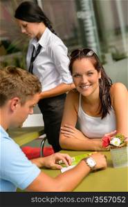 Couple at cafe man looking at menu woman smiling restaurant