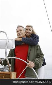 Couple at helm of sailboat, smiling