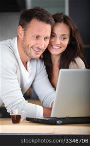 Couple at home connected on internet with laptop computer