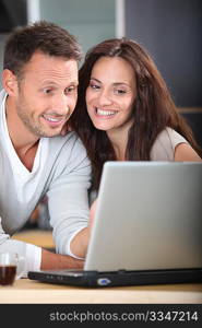 Couple at home connected on internet with laptop computer