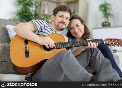 couple at home man playing guitar