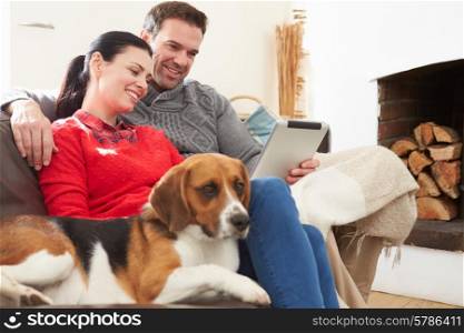 Couple At Home With Pet Dog Looking At Digital Tablet