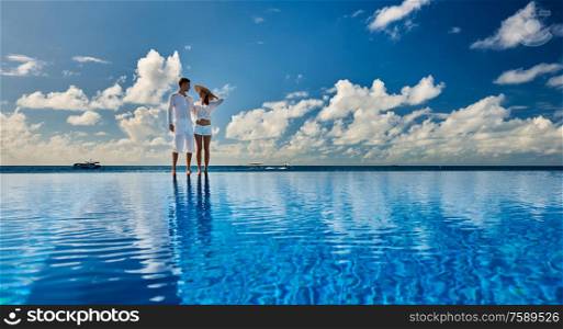 Couple at infinity pool poolside against sky