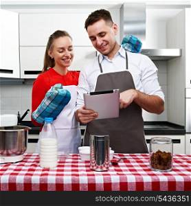 Couple at kitchen cooking together with tablet pc