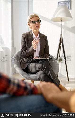 Couple at psychologists office. Focus on psychologist talking to young spouse holding hands. Female psychologist talking to couple at consultation