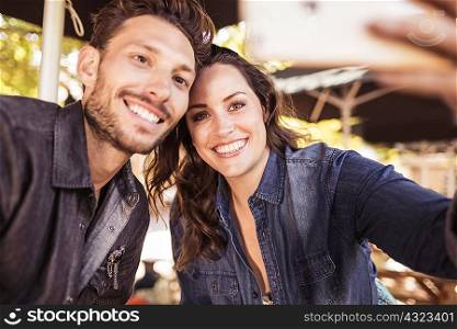 Couple at sidewalk cafe taking selfie