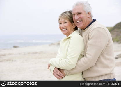 Couple at the beach embracing and smiling