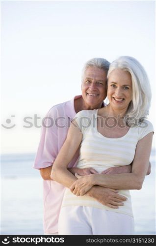 Couple at the beach embracing and smiling