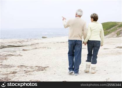 Couple at the beach holding hands and pointing