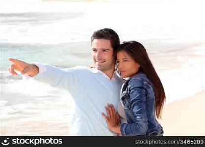 Couple at the beach, man showing something to girl