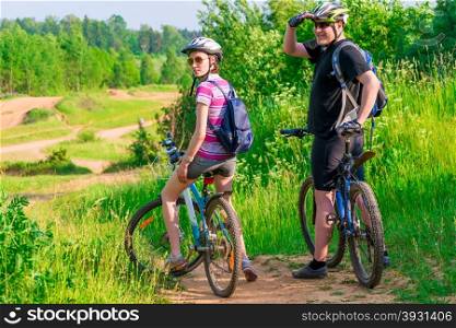 couple athletes on the mountain bike resting on a hill