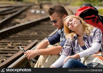 Couple backpack traveling resting on railroad map happy direction tired