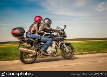 Couple Bikers in a leather jacket riding a motorcycle on the road