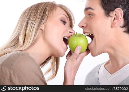 Couple biting into green apple