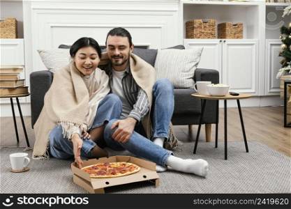 couple blanket watching tv eating pizza