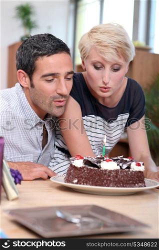 Couple blowing birthday candle