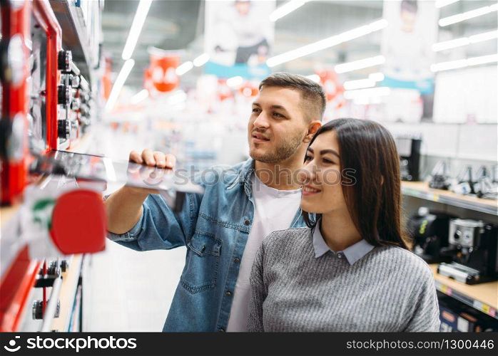 Couple buys an electric oven in a supermarket. Customers in shop, family choosing consumer goods. Couple buys an electric oven in a supermarket