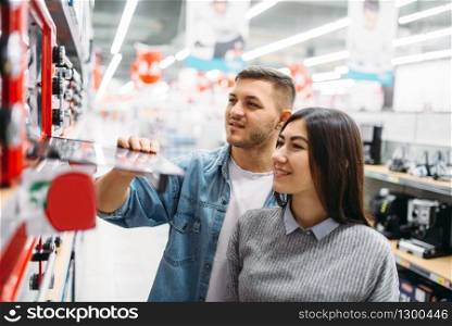 Couple buys an electric oven in a supermarket. Customers in shop, family choosing consumer goods. Couple buys an electric oven in a supermarket