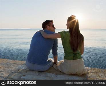Couple by sea watching sun set
