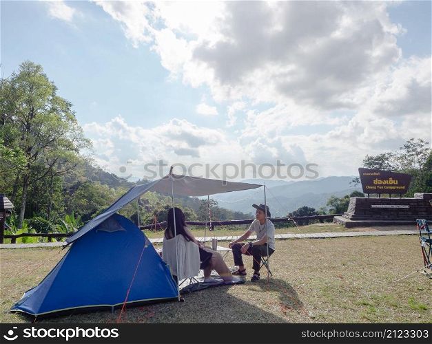 Couple camping and enjoy nature landscape on view point at Mae Wong national park, landmark in Kamphaeng Phet, Thailand. location sign in Thai language translate in English is be Chong Yen Campground
