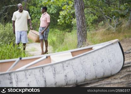 Couple carrying a basket and walking towards a boat