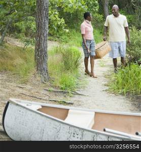 Couple carrying a basket and walking towards a boat