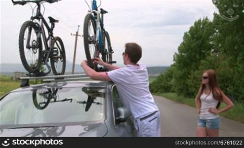 Couple carrying bicycles on the roof of his car