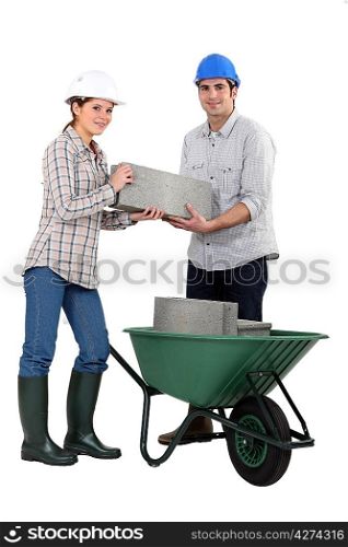 Couple carrying bricks in wheelbarrow