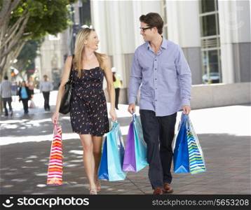 Couple Carrying Shopping Bags On City Street