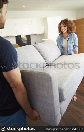 Couple Carrying Sofa As They Move Into New Home