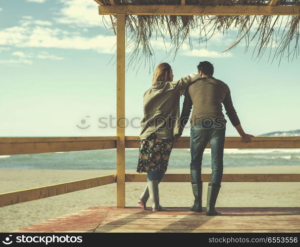 Couple chating and having fun at beach bar. Happy couple enyojing time together on beach during autumn day colored filter