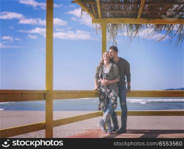 Couple chating and having fun at beach bar. Happy couple enyojing time together on beach during autumn day colored filter