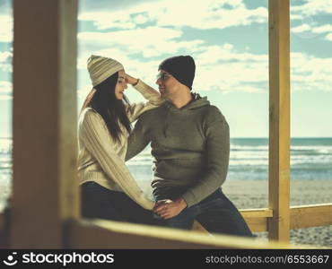 Couple chating and having fun at beach bar. Happy couple enyojing time together on beach during autumn day colored filter