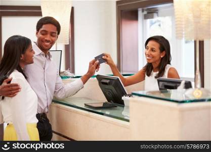 Couple Checking In At Hotel Reception