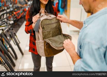 Couple choosing tourist equipment for travelling, shopping in sports shop. Summer season extreme lifestyle, active leisure store, customers buying backpack